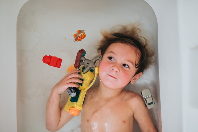 child playing in bath tub with water